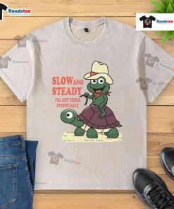 Alt Text: Funny slow and steady cowboy turtle frog on a washed t-shirt, promoting a humorous take on patience and perseverance.