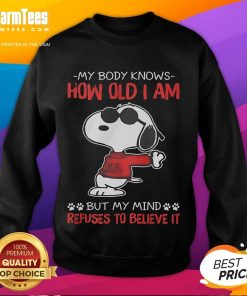 Funny Snoopy sweatshirt with 'My body knows how old I am but my mind refuses to believe it' design.