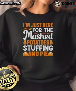 Funny Thanksgiving sweatshirt featuring the phrase 'I'm just here for mashed potatoes, stuffing, and pie' in festive colors.
