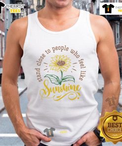 Happy person wearing 'Feel Like Sunshine' tank top, standing close to friends in a sunny outdoor setting, radiating joy.