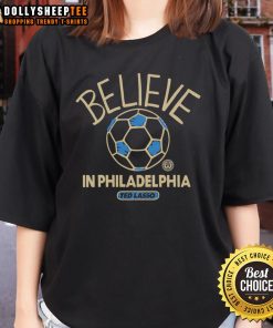 Alt Text: Happy Ted Lasso wearing a Believe tee in Philadelphia, showcasing positivity and team spirit in vibrant colors.