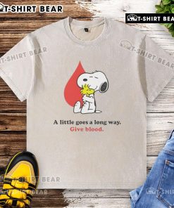 Alt Text: Snoopy graphic on a washed t-shirt promoting blood donation with the phrase A Little Goes A Long Way for Give Blood campaign.