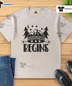 Nice Adventure Begins washed t-shirt displayed on a rustic wooden background, showcasing its soft fabric and relaxed fit.