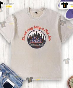 Alt Text: Official New York Mets It's Not Easy Being A Mets Fan MLB washed t-shirt displayed on a wooden background.