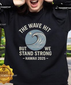 Alt Text: Official The Wave Hit But We Stand Strong Hawaii 2025 Sweatshirt featuring bold graphics and vibrant colors.