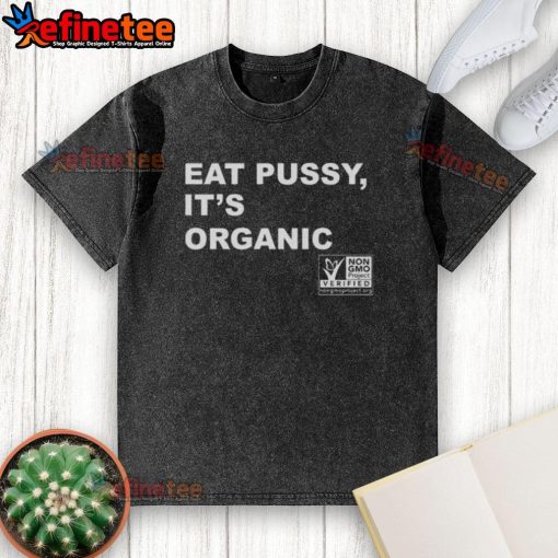 Original Eat Pussy It's Organic Non-GMO Project Verified washed t-shirt displayed on a wooden background.