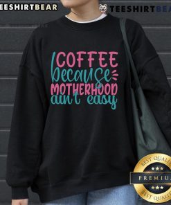 Cozy 'Pretty Coffee Because Motherhood Ain't Easy' sweatshirt displayed with a cup of coffee, perfect for moms seeking comfort.