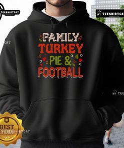 Happy family enjoying turkey pie and football, wearing cozy hoodies for a festive Thanksgiving celebration.