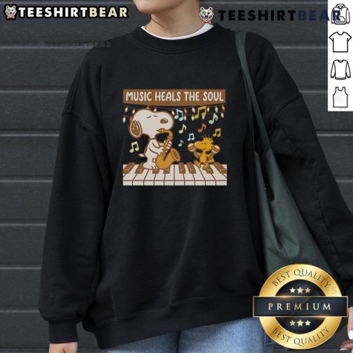 Cozy Snoopy and Woodstock sweatshirt featuring 'Music Heals The Soul' design, perfect for fans of Peanuts and music lovers.