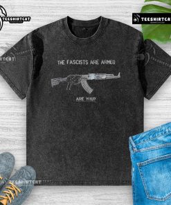 Top The Fascists Are Armed Are You washed t-shirt design featuring bold text on a stylish cotton fabric.