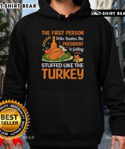 Person wearing 'Top-The-First-Person-Who-Bashes-The-President-Is-Getting-Stuffed-Like-The-Turkey' hoodie, smiling.