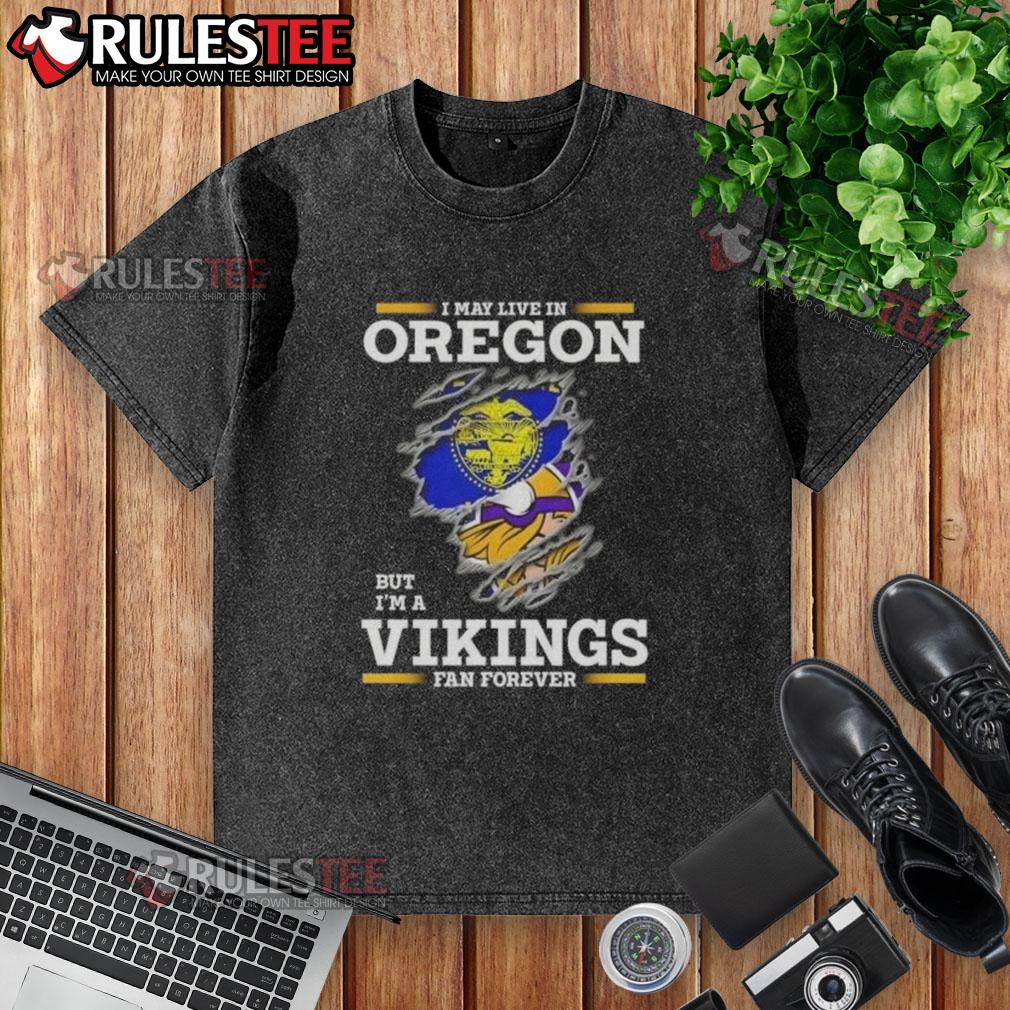 Awesome I May Live In Oregon But I'm A Minnesota Vikings Fan Forever Washed T-Shirt Awesome washed t-shirt featuring 'I may live in Oregon, but I'm a Minnesota Vikings fan forever' design in bold lettering.
