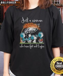 Alt Text: Woman in a Philadelphia Eagles tee enjoying fall, surrounded by autumn leaves and peanuts, showcasing her love for football.