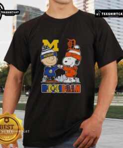 Alt Text: Cute Snoopy and Charlie Brown in Michigan sports Wolverines X Detroit Tigers skyline t-shirt design.