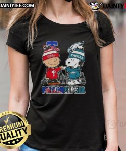 Cute Snoopy and Charlie Brown in Philadelphia sports gear featuring Phillies and Eagles skyline on ladies tee.
