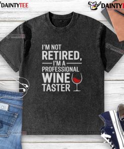 Funny 'I'm Not Retired, I'm A Professional Wine Taster' washed t-shirt displayed on a wooden background.