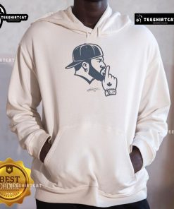 Vladimir Guerrero Jr. wearing a Toronto Blue Jays hoodie, showcasing his signature shush gesture on the field.