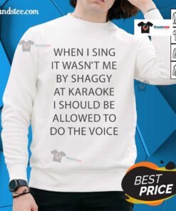 Person wearing 'Good When I Sing It Wasn't Me By Shaggy' sweatshirt at karaoke, enjoying the performance.
