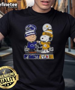 Happy Charlie Brown wearing a Penn State Nittany Lions & Pittsburgh Steelers skyline t-shirt, showcasing team spirit.