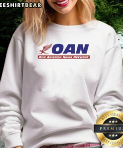 Alt Text: Hot Mike Gundy wearing a One America News Network sweatshirt during a press conference, showcasing team spirit.