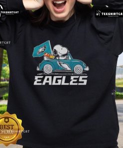 Philadelphia Eagles flag sweatshirt featuring Snoopy and Woodstock driving a car, perfect for fans and cozy wear.