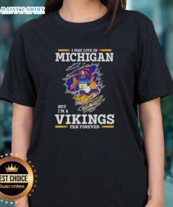 Official ladies tee featuring 'I May Live In Michigan But I'm A Minnesota Vikings Fan Forever' design.