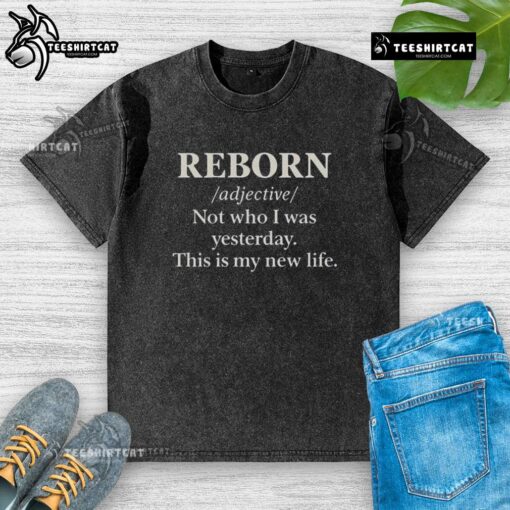 Official Reborn 'Not Who I Was Yesterday, This Is My New Life' washed t-shirt displayed on a wooden background.