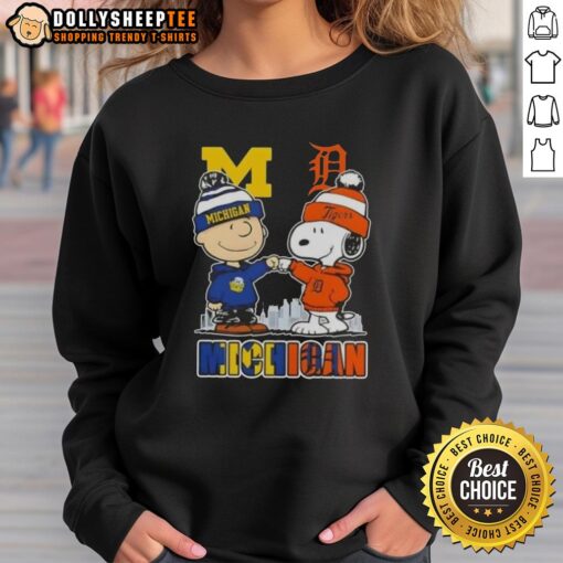 Alt Text: Cozy sweatshirt featuring Snoopy and Charlie Brown, showcasing Michigan Wolverines and Detroit Tigers skyline design.