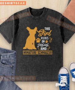Girl wearing a washed T-shirt that says 'This Girl Runs on Jesus and Miniature Schnauzer' with a cute schnauzer by her side.