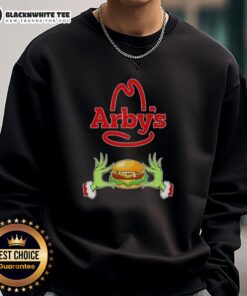 Happy Grinch hands holding a heart in front of an Arbys Merry Christmas sweatshirt, festive and cheerful holiday spirit.