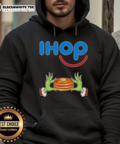 Alt Text: Happy Grinch hands making a heart shape, wearing a Merry Christmas IHOP hoodie, perfect for festive celebrations.