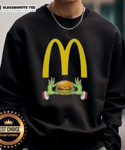 Happy Grinch hands holding a McDonald's cup on a Merry Christmas sweatshirt, perfect for festive holiday cheer.
