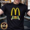 Happy Grinch hands holding a McDonald's logo on a Merry Christmas T-shirt, perfect for festive holiday cheer.