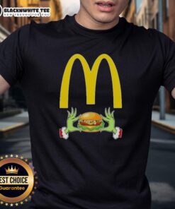 Happy Grinch hands holding a McDonald's logo on a Merry Christmas T-shirt, perfect for festive holiday cheer.