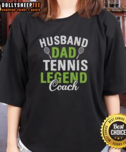 Happy husband and dad coaching tennis, wearing a ladies' tee, showcasing his passion for the sport and family.