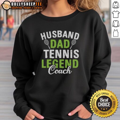 Happy husband and dad wearing a Tennis Legend Coach sweatshirt, smiling on the court with a tennis racket in hand.