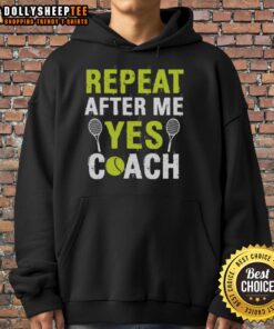 Happy tennis coach wearing 'Repeat After Me Yes' hoodie, inspiring players on the court with positive energy.