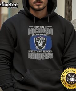 Fan wearing 'Hot I May Live in Michigan But on Gameday My Heart and Soul Belongs to Raiders' hoodie, showing team spirit.