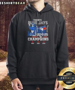 Alt Text: Toronto Blue Jays mascot in Nice 2025 American League Champions hoodie with a skyline backdrop.