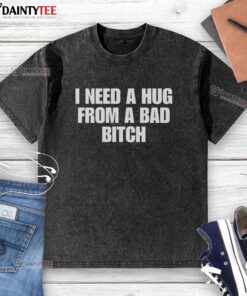 Nice I Need A Hug From A Bad Bitch washed t-shirt displayed on a hanger, featuring bold text and a casual style.
