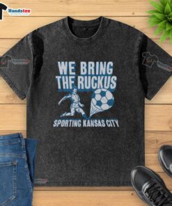 Nice Sporting Kansas City We Bring The Ruckus washed t-shirt displayed on a hanger, showcasing its vibrant design and colors.