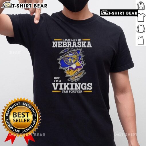Official I May Live In Nebraska But I'M A Minnesota Vikings Fan Forever T-Shirt in purple and gold with team logo.