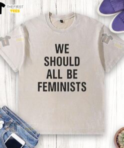 Alt Text: Pretty We Should All Be Feminists washed t-shirt displayed on a wooden table, promoting gender equality and empowerment.