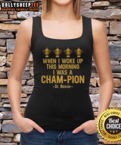 Dr. Rassie wearing a 'Pretty When I Woke Up This Morning I Was A Cham Pion' tank top, showcasing vibrant morning style.