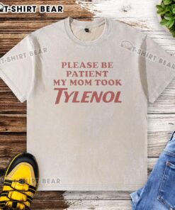 Top Please Be Patient My Mom Took Tylenol washed t-shirt displayed on a hanger, featuring humorous text design.