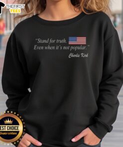 Charlie Kirk wearing a US flag sweatshirt that says 'Stand for Truth Even When It's Not Popular.'