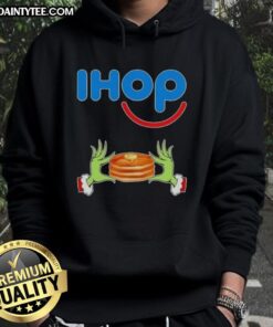 Good Grinch hands holding a mug, wearing a Merry Christmas IHOP hoodie in festive colors.