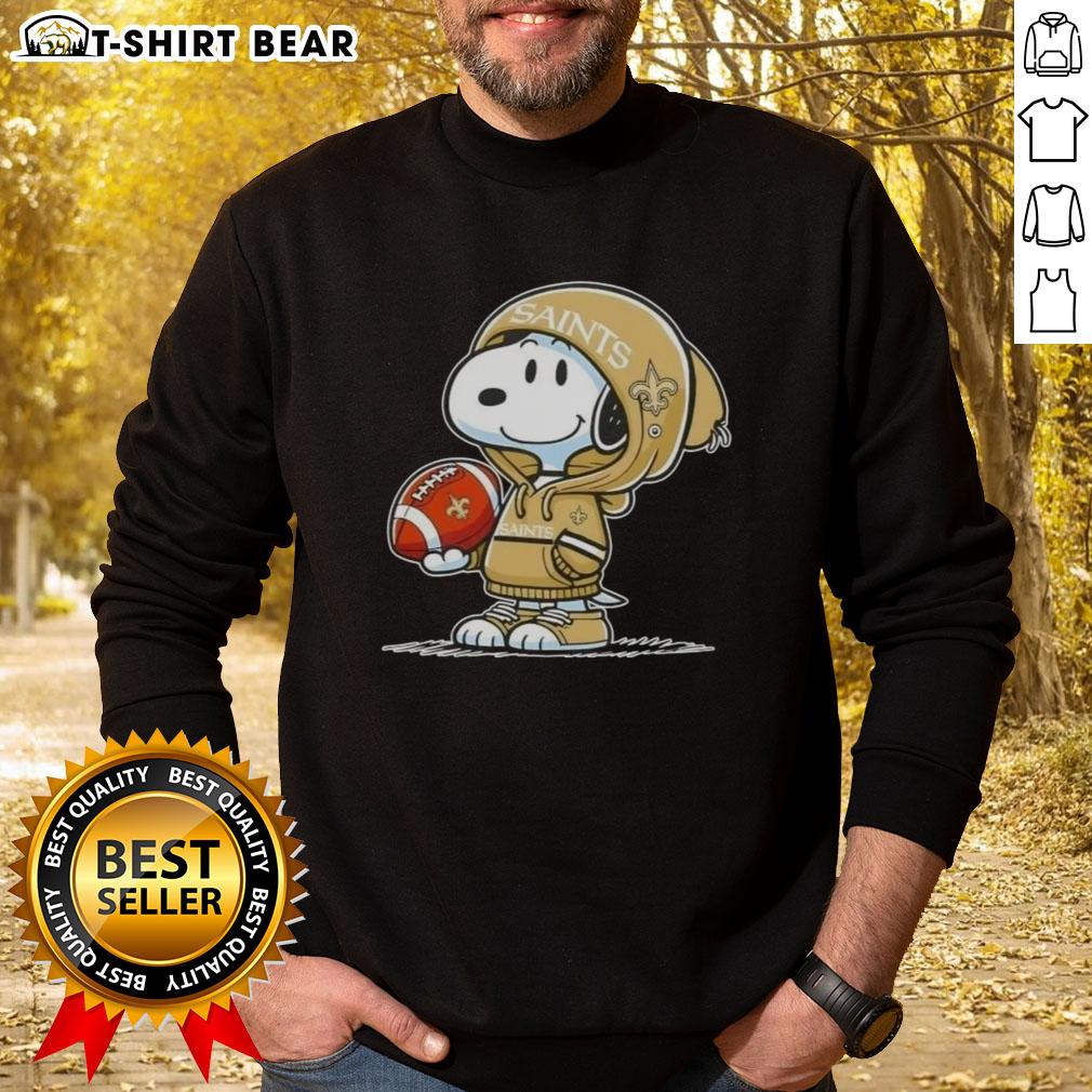Official Peanuts Snoopy Wearing Hoodie New Orleans Saints And Smilling At Fans Sweatshirt Alt Text: Snoopy in a hoodie supporting the New Orleans Saints, smiling at fans, featured on a stylish sweatshirt.