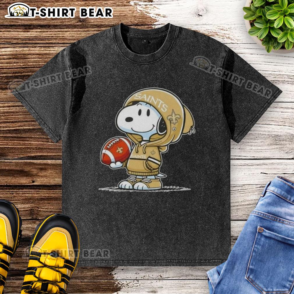 Official Peanuts Snoopy Wearing Hoodie New Orleans Saints And Smilling At Fans Washed T-Shirt Alt Text: Snoopy in a hoodie, smiling at fans, showcasing the Official Peanuts New Orleans Saints washed t-shirt design.