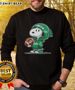 Alt Text: Snoopy in a New York Jets hoodie smiling at fans, showcasing the official Peanuts sweatshirt design.